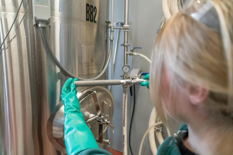 person wearing gloves while fixing distillation tank